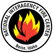 circular text "National Interagency Fire Center, Boise, Idaho" on emblem surrounding a red and yellow illustration of fire on a black field