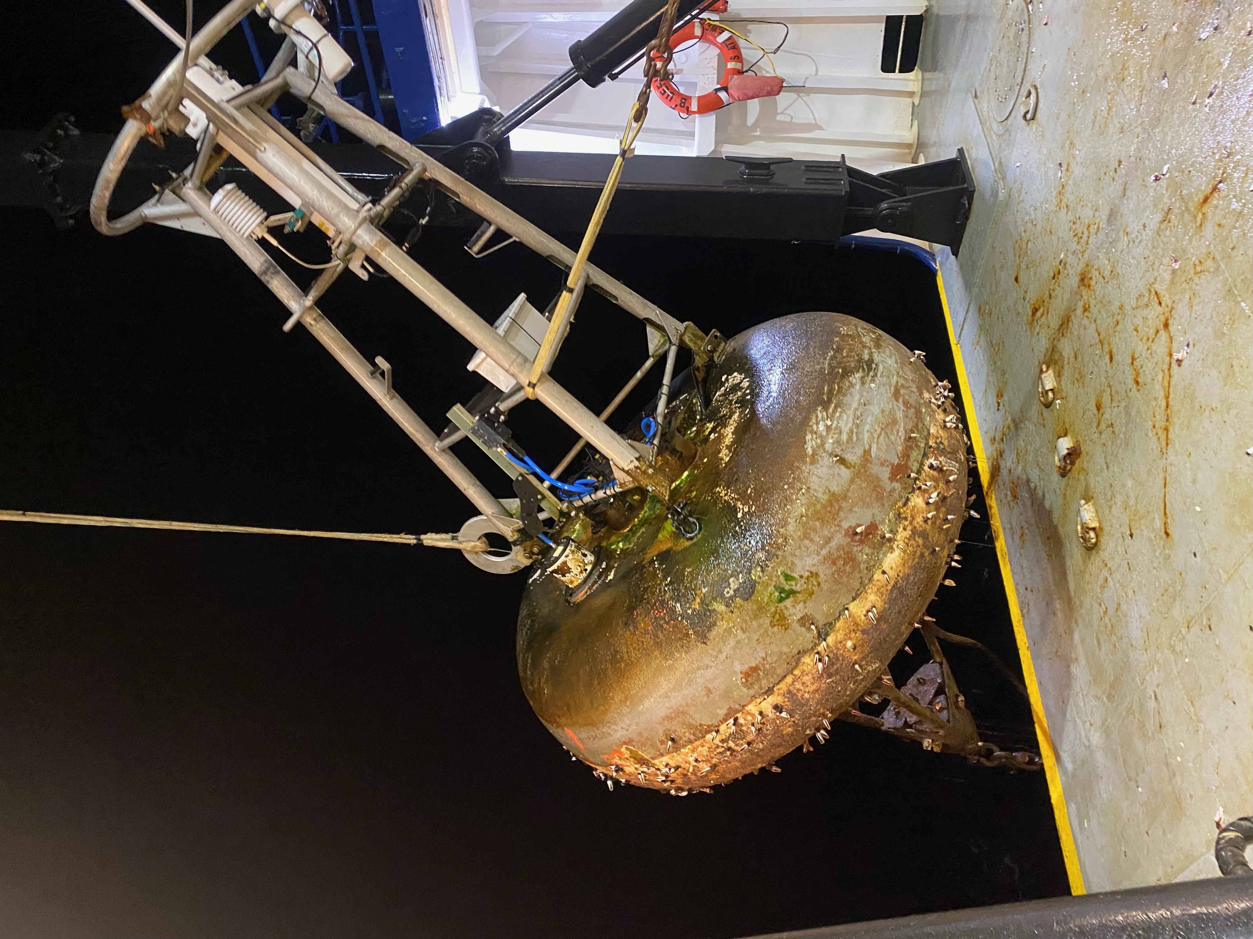 Nighttime retrieval of a TAO buoy. Technicians pulled this buoy aboard and deployed a new one. When a buoy has been in the water for a long time it may have shell life on the hull (seen here), which could result in injury to the crew. Technicians disassembled the buoy, pressure washed the hull and mounted a new mast and sensors. The refurbished buoy was deployed in a new location.  