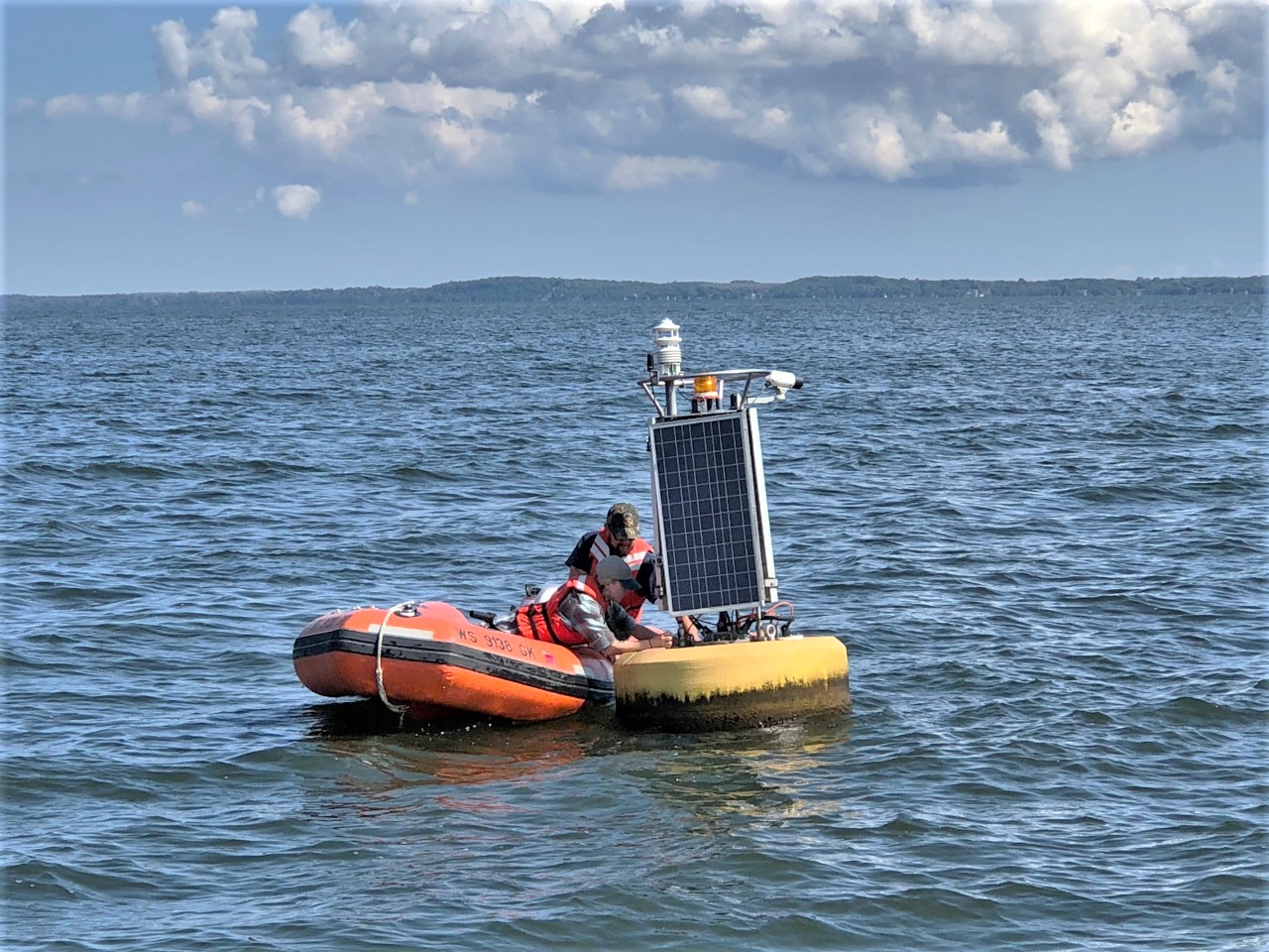 Two men in small launch repair buoy in Lake Michigan