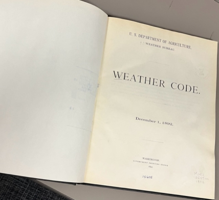Photo of the title page of the Weather Bureau’s 1892 Weather Code book. It reads, "U.S. Department of Agriculture, Weather Bureau, Weather Code. December 1, 1892. Washington, Government Printing Office. 1892." The number 15605 is handwritten at the bottom. In the lower write another handwritten note reads, "Moq.1, U587wc, 1892."