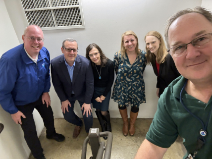 Huddle up! NWS Director, Ken Graham (far left) and NWS employees take a #SafePlaceSelfie at work: An interior stairwell at the lowest level of the building, with no windows.