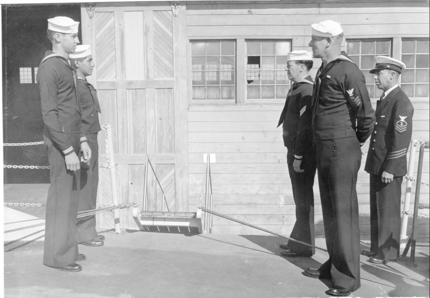 A black and white photo of USC&GS Sailors and a Chief Petty Officer, all in uniform. The sailors wear the "Dixie Cup," a round, white hat with an upturned brim all the way around.