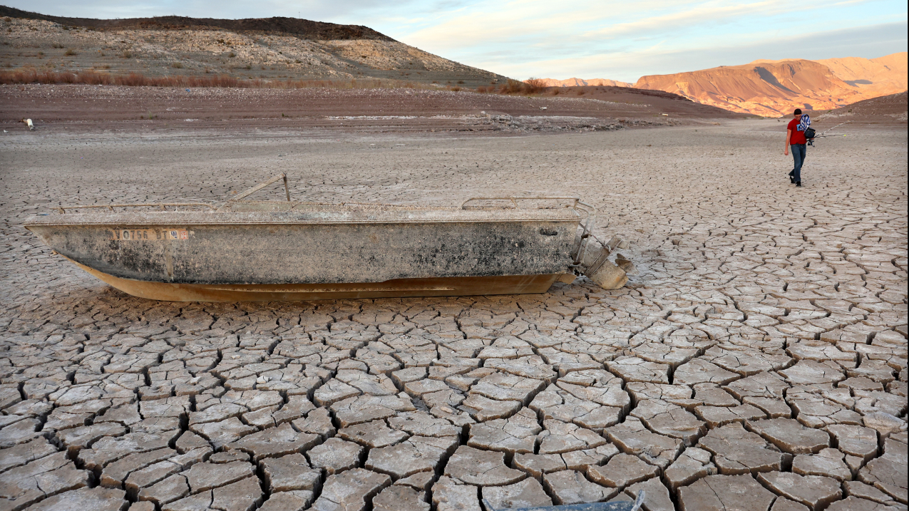 A person walks past a formerly sunken boat resting on a now-dry section of lakebed at Lake Mead on May 10, 2022.