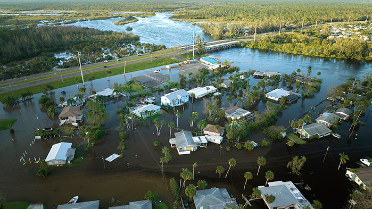 An aerial photograph of a flooded neighborhood near a river.