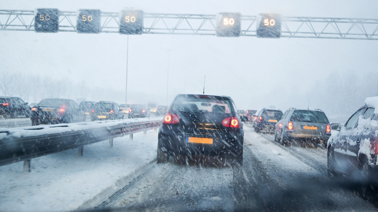 Photo of snow and rain covered roadway with cars.