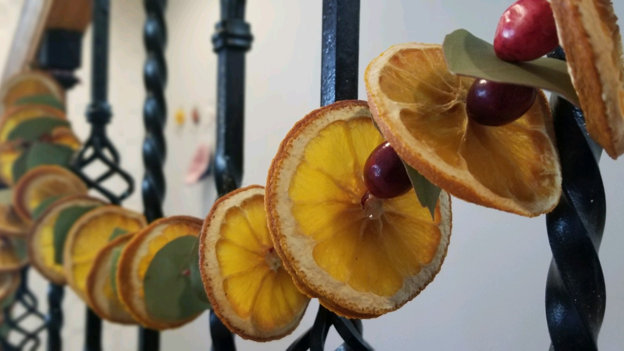 A garland made out of dried oranges, cranberries, and eucalyptus hung on a stairway banister.