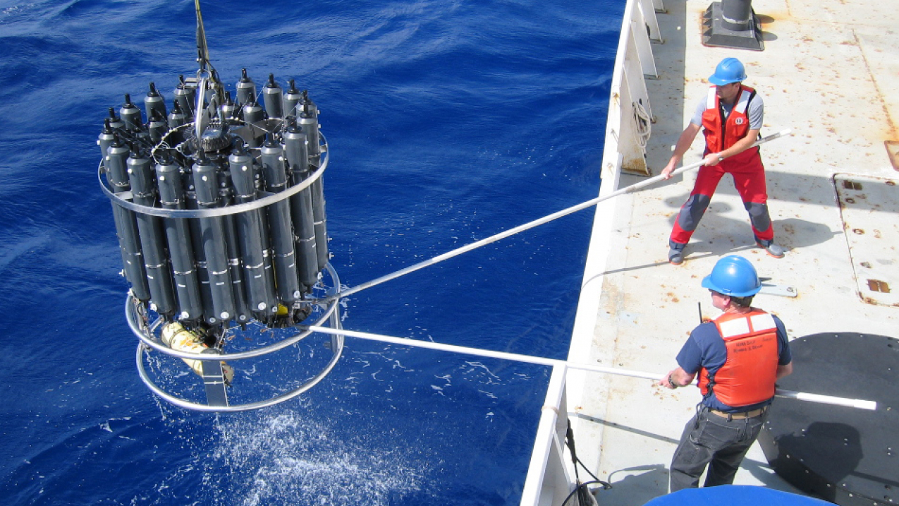 Scientists raise a rosette loaded with water samples to measure carbon dioxide in the ocean.