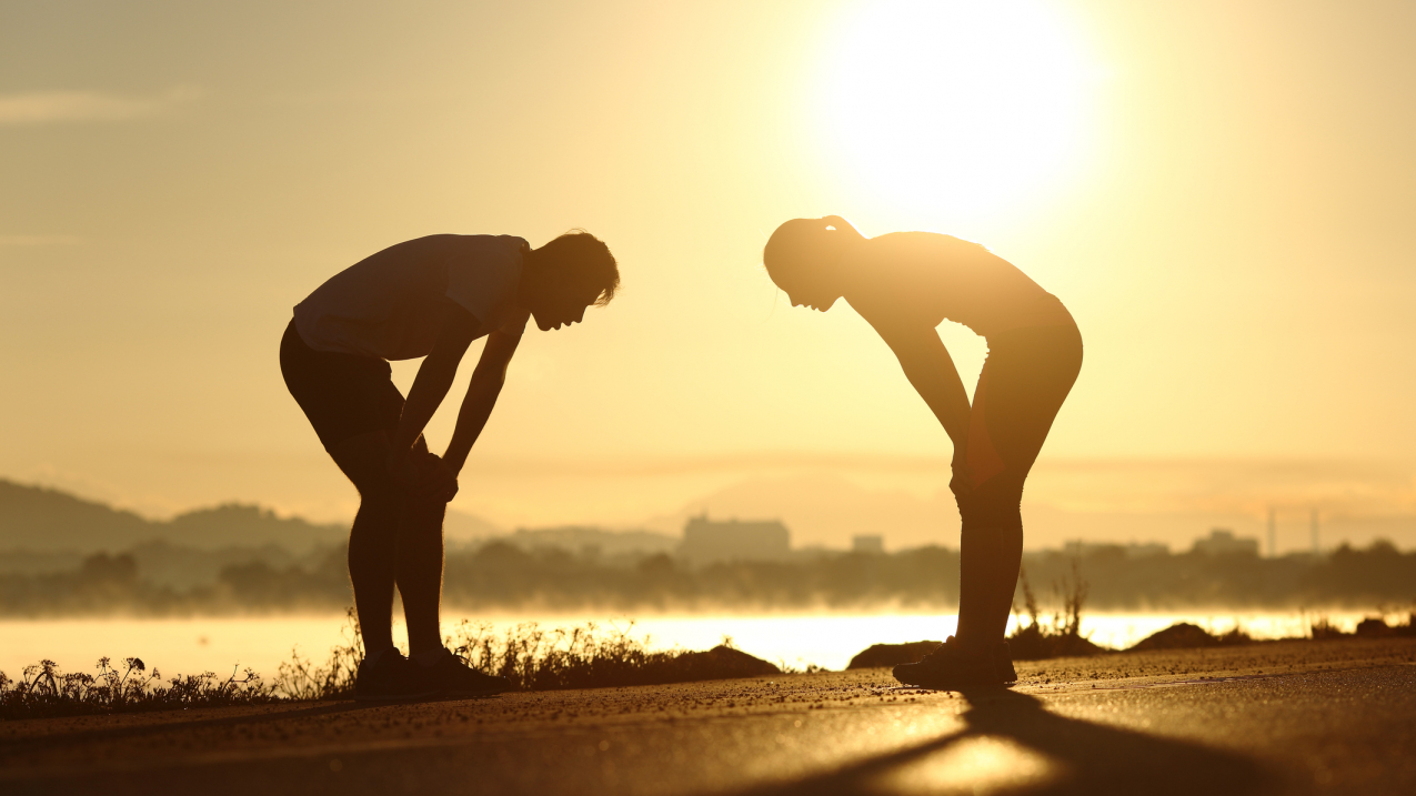Stock image of 2 people taking a moment to recover from exercise in the high heat of the day.