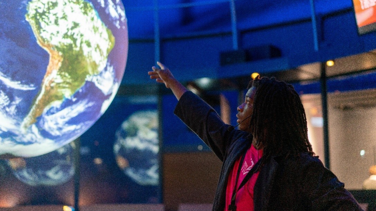 Teen Myles Williamson gestures at the large Earth interactive during a presentation on acid rain using the Science on a Sphere at the Museum of Science and Industry in November 2019.