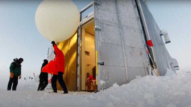 Lt. Timothy Holland, NOAA Corps, emerges from a balloon assembly station with an ozonesonde attached to a weather balloon before releasing it over the South Pole.