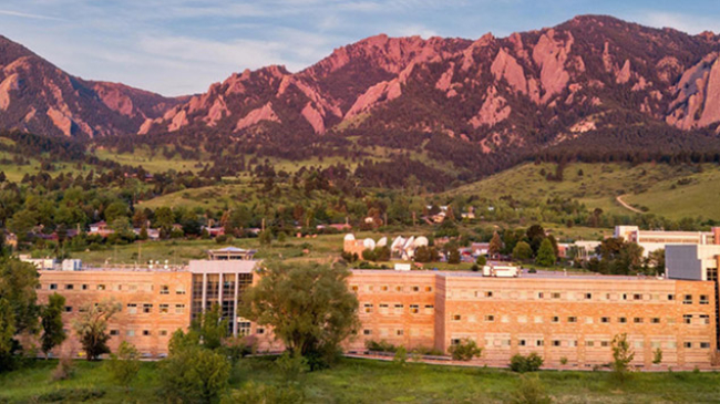 A scenic view of a wide office building with the Rocky Mountains in the background.