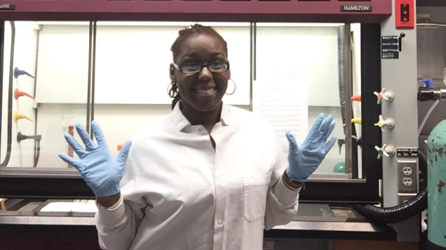 Shareena Cannonier in a white lab coat and blue medical gloves.