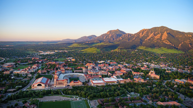 2021 aerial photo shows Boulder from the north with the University of Colorado campus in the foreground and the Flatirons in the background.