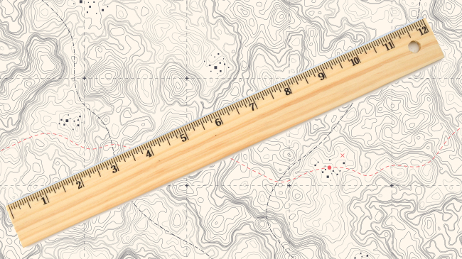 Image of a Wooden ruler placed against a generic land map. On New Year's Eve 2022, NOAA and the National Institute of Standards and Technology (NIST) will retire the U.S. survey foot and replace it with the international foot.