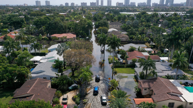 In this aerial view, cars navigate through flooded streets after record rains fell in the area on April 13, 2023, in Hollywood, Florida. In Fort Lauderdale, this 1,000-year rain event smashed the previous one-day record of 14.59 inches of rainfall set on April 25,1979.