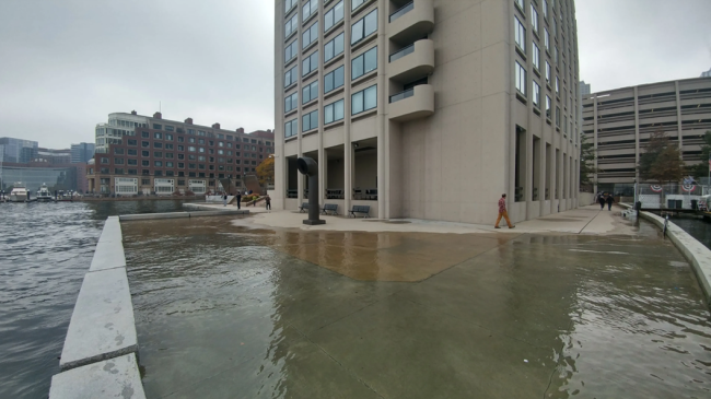 High tide flooding pushes water onto a walkway along the Boston waterfront near India Wharf in 2016.