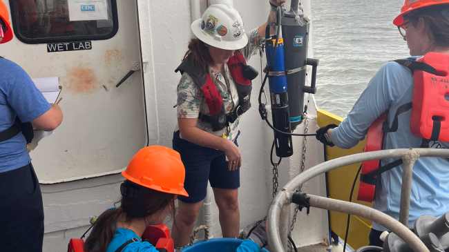 Photo showing scientists MacKenzie Smith from LUMCON (back center), Abby Roche from LSU (front center) and Emily Savoie from LSU (right) collect near-bottom water aboard the R/V Pelican to obtain oxygen measurements used to determine the size of the Gulf of Mexico hypoxic zone.