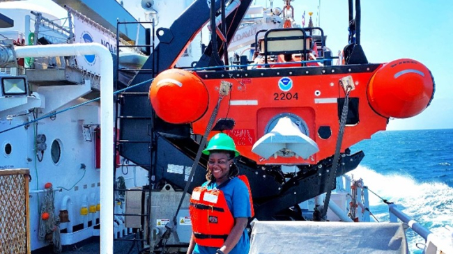 An image of Victoria Obura standing on the deck of NOAA Ship Thomas Jefferson in front of the fast rescue boat.