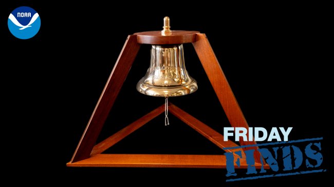 A photo of the bell from the USC&GS Ship Hydrographer. The bell hangs from a cherrywood pyramid-shaped frame.