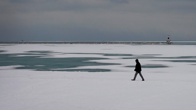 Photo of a man walking along the snow-covered shoreline of Lake Michigan on January 24, 2022 in Chicago, Illinois. After two days of snow, Chicago and much of the Midwest are now bracing for an Arctic blast that is expected to drop temperatures into the single digits and below for the next couple of days. 