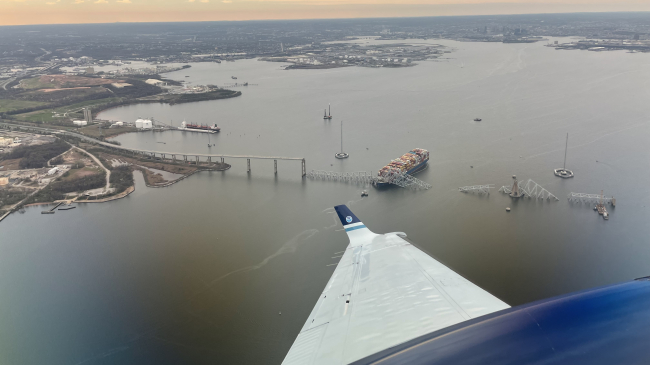March 28, 2024: View from NOAA King Air N68RF during a navigation survey following the collapse of the Francis Scott Key Bridge. The bridge and the MV Dali, which collided into it, are visible.
