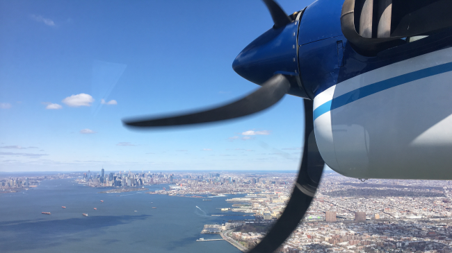 A NOAA Twin Otter aircraft fitted with data-collecting instruments approaches New York City from over the Hudson River during an airborne research mission in 2018.