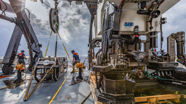 Two NOAA staff work on a ship deck full of technology.