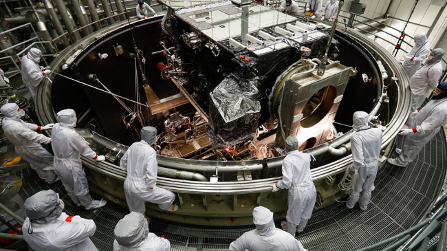 Engineers watch the GOES-S Satellite being lowered into the thermal vacuum chamber.