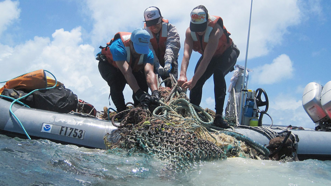 Scientists load onto a small boat marine debris collected at Midway Atoll in Papahanaumokuakea Marine National Monument.