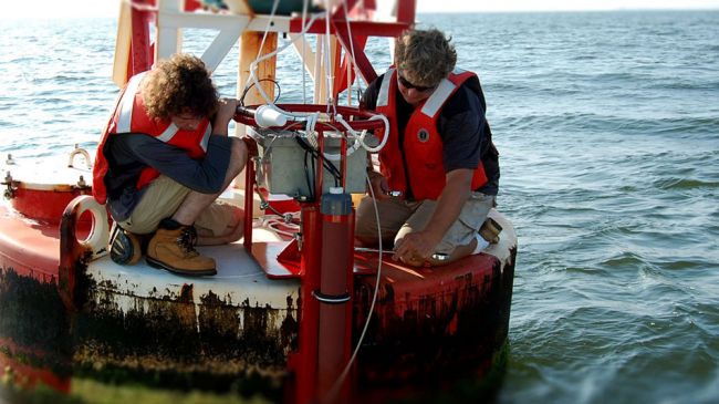 Max Ivanov and Scott Mowery with NOAA's Center for Operational Oceanographic Products and Services install an improved current sensor system on a navigation buoy in Chesapeake Bay. The system transmits real-time current speed and direction observations via satellite to help mariners more safely navigate busy shipping channels.