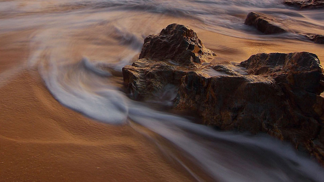 Ocean waves recede along a rocky beach shoreline.