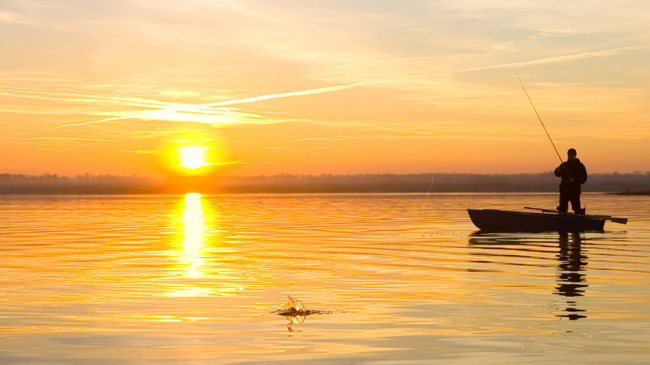 Fisherman on a boat at sunset.