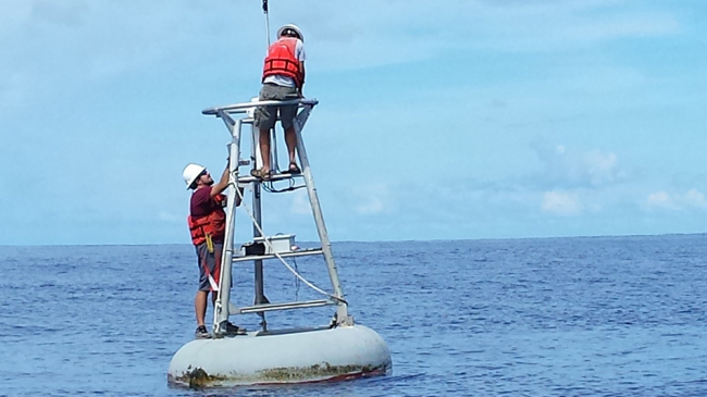 NOAA technicians service a buoy in the Pacific Ocean designed to provide real-time data for ocean, weather and climate prediction.