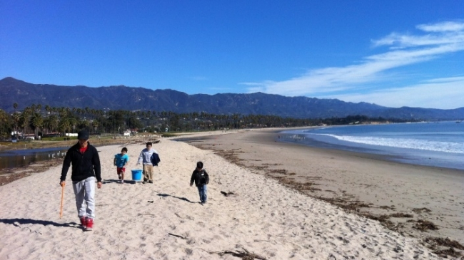  Three students and an adult walking along an empty beach.