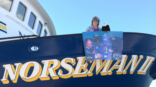 Teacher at Sea Mary Cook and school mascot Qanuk the Eagle show off a banner created by Scammon Bay School's 4th Grade class on board R/V Norseman II.