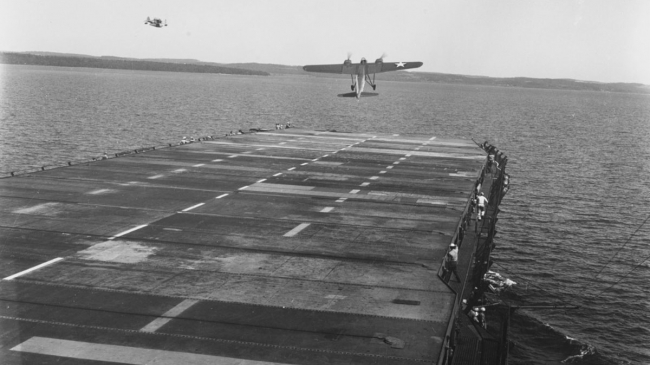 The U.S. Navy launches the TDN-1 Drone while steaming off Traverse City, Michigan, during flight tests on August, 10, 1943. This plane has assumed an excessive nose-up attitude and is probably about to stall. The Navy used these aircraft to train and certify pilots to take off and land from aircraft carriers during World War II. As this was a training site, crashes and emergency water landings were frequent. The U.S. Coast Guard operated small yard patrol craft to rescue the pilots and drop a buoy over