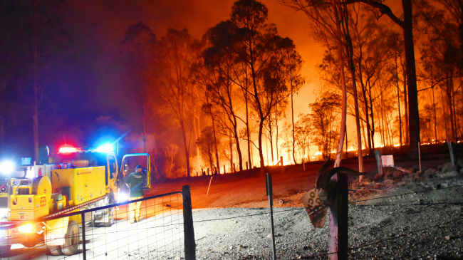 December 19, 2019: A lone fire appliance at the farm gate on the edge of the Gregory River fire near Bundaberg, Queensland, Australia. Up to 18 trucks and water-bombing helicopters were deployed to the biggest fires ever seen in the area.