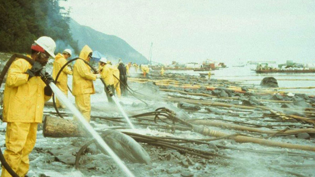 Workers hose off oil from a rocky shore in Alaska following the Exxon Valdez oil spill. Photo dated April 1989. 