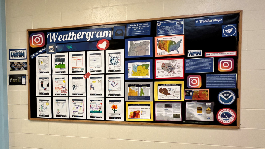 A bright and colorful board in a school hallway that says "Weathergram, #WeatherSlaps, @CoCoRaHS." It features 15 illustrations that resemble Instagram posts with weather information and safety messages such as "When thunder roars, go indoors." The board also includes weather maps and logos for NOAA, the National Weather Service, Weather Ready Nation Ambassadors, and Instagram. 
