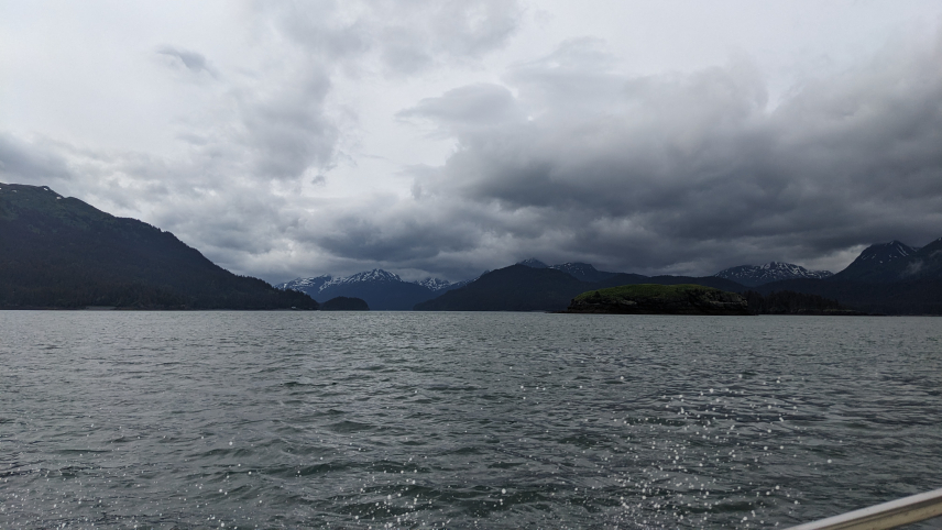 A landscape of water with mountains in the background on a gray, overcast day.