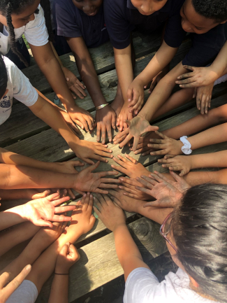 A group of students show off their dirty hands in a circle.