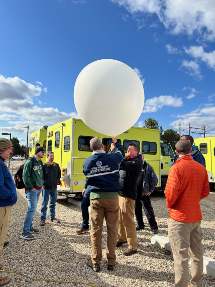 Photo showing IMETs practice launching a weather balloon during 2023 IMET training. Meteorologists use upper air observations from weather balloons to develop a forecast.