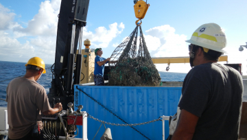 NOAA Ship Oscar Elton Sette crew loading collected debris into a storage container on the deck for transport back to Honolulu.
