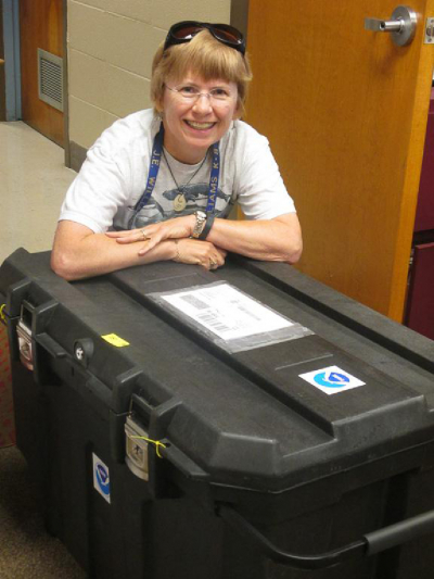 Teacher at Sea Sue Zupko poses with the shipment containing the drifter buoy her class adopted in 2014. 