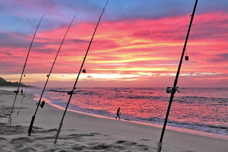 Fishermen shoreline fishing on the coast of Lanikai beach, Hawaiʻi during sunset.