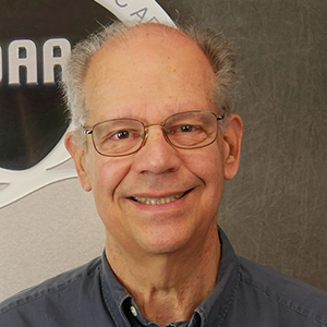 A photo of Michael Kraus in a grey button-down shirt, looking at camera.