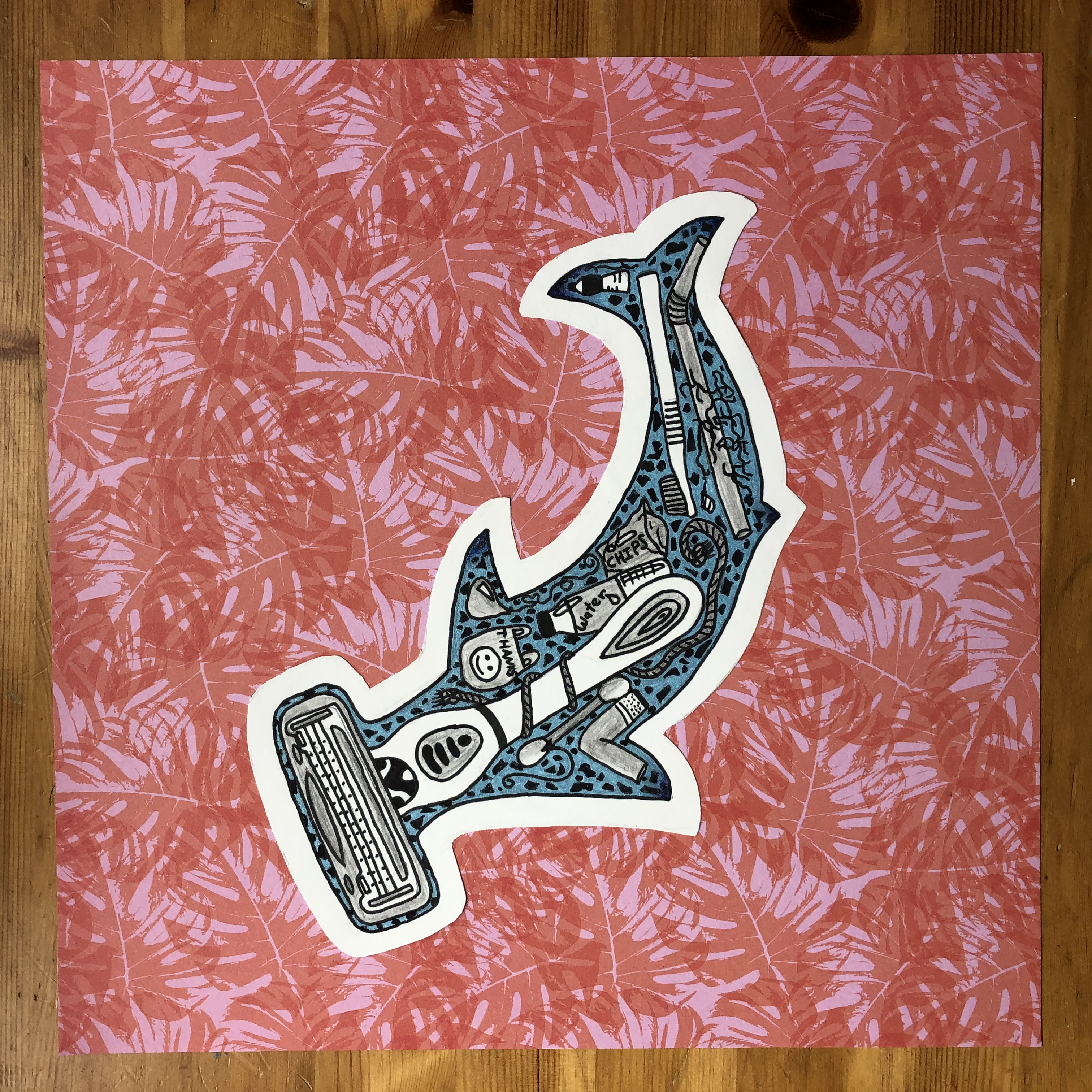 Youth artwork shows a stylized silhouette of a hammerhead shark that is filled with marine debris, including a razor, cotton swap, plastic bag, toothbrush, straw, water bottle, and rope. It is set on a background of tropical leaves.