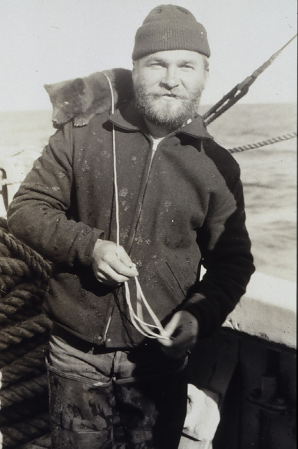 Crewman Alaskin stands with the USC&GSS Pioneer’s pet fox on his shoulder.