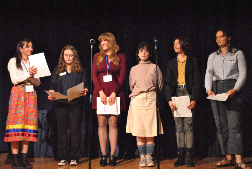 Six young people reading a poem on stage.