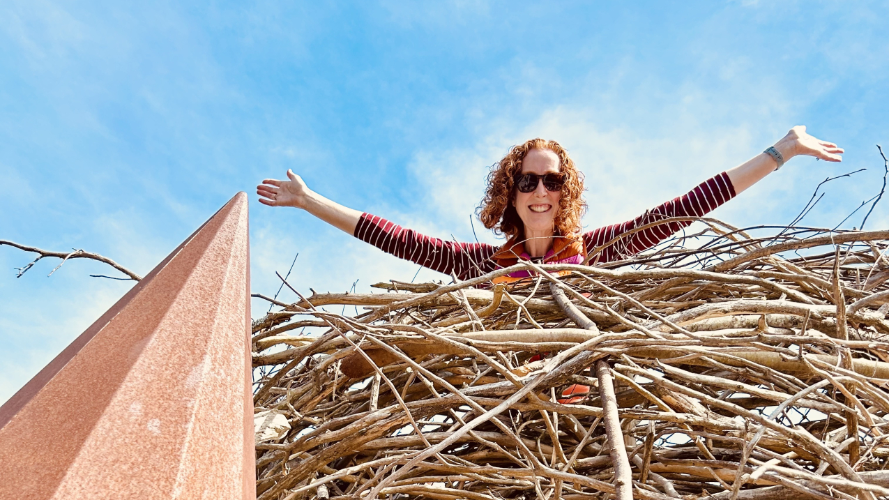 A woman smiling down from a giant eagle's nest (6 foot diameter).